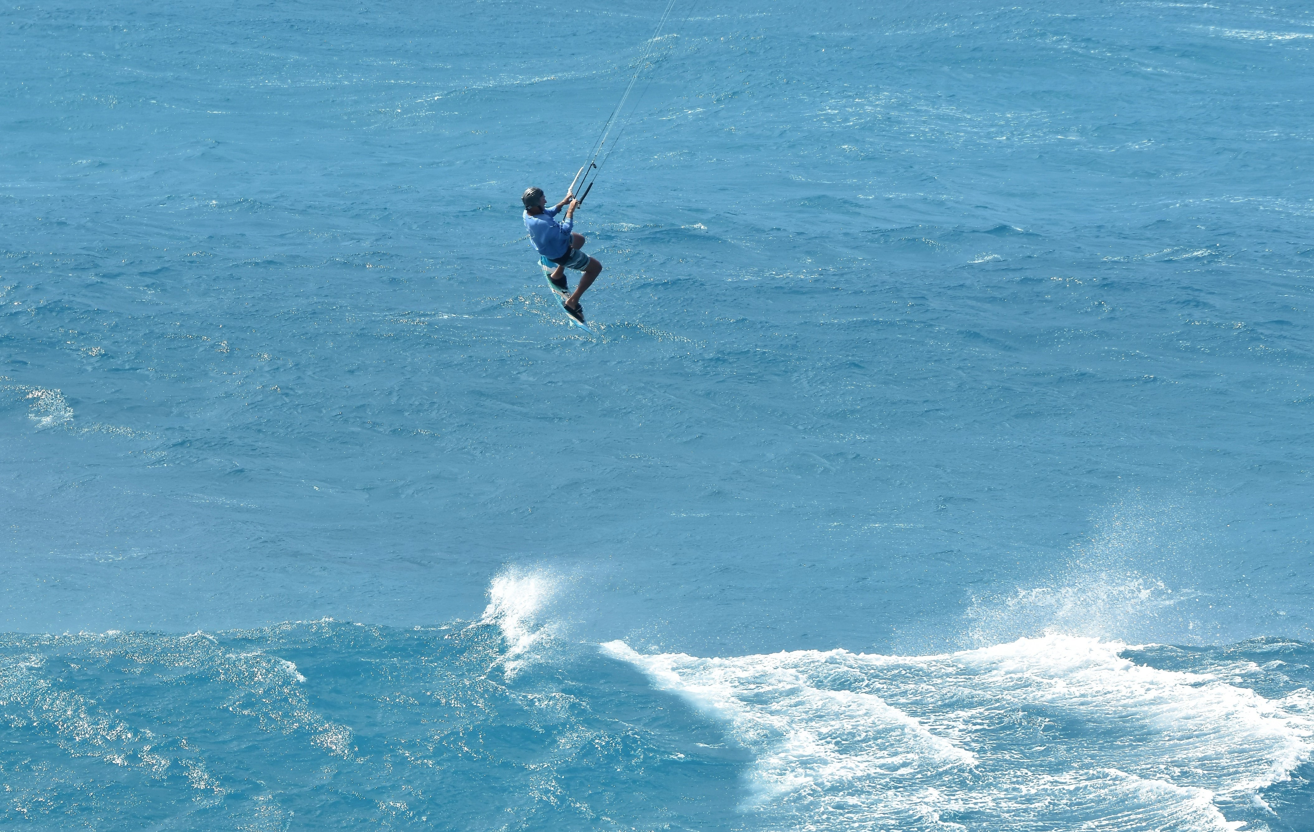 A person kite surfing in the ocean, skillfully maneuvering the board while being pulled by a colorful kite.